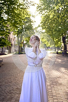 chic middle age woman in a white vintage dress in a sunlit alley