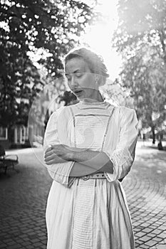 chic middle age woman in a white vintage dress in a sunlit alley