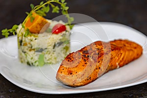 Chic plate of grilled salmon with broccoli rice garnished with fine herbs.