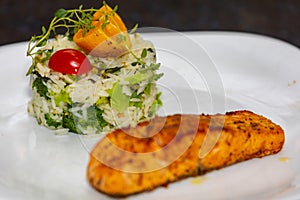 Chic plate of grilled salmon with broccoli rice garnished with fine herbs.