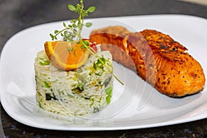 Chic plate of grilled salmon with broccoli rice garnished with fine herbs.