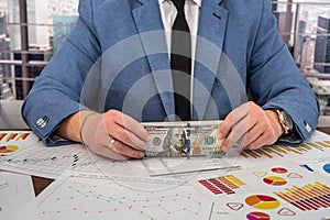 chic young male businessman calculates his business graphs at the office desk.