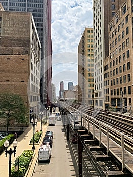 View of Chicago Loop on Wabash Ave, where el tracks cast patterns onto street below, and clouds cover the sky while train