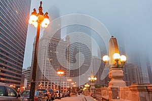 Chicago street as mist descends and lights come on Upper Wacker Drive with ornate lights tall buildings rising into fog photo