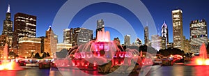 Chicago skyline illuminated at dusk with colorful Buckingham fountain on the foreground