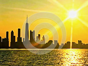 Chicago skyline seen from Lake Michigan, with sunset and sunbeams extending over cityscape during summer