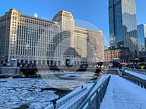 Chicago winter featuring snow covered riverwalk, ice chunks on river and commuters bundled up