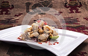 Chicharon de pescado is a Peruvian food of fried marinated fish with onion, aji and lemon. Peruvian food