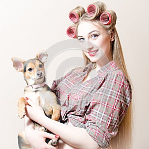 Chick & puppy: beautiful blond pinup girl with red lips & curlers in her hair holding a small cute dog happy smiling