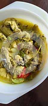 Chicked soup cooked with yellow herbs and other spices in the bowl