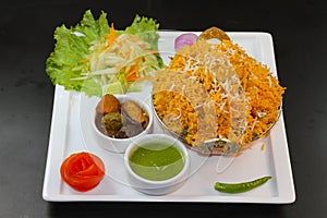 Chicken biryani with salad, raita, mint chutney and pickle served in a karahi isolated on dark background side view of indian