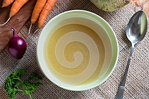 Chicken bone broth in a green soup bowl, top view photo