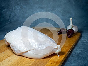 Chicken breast on a cutting board. Still life on a black background. hot pepper and garlic around a piece of meat