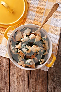 Chicken breast stewed with spinach in a saucepan. Vertical top v