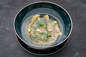 Chicken broth with dill, consomme, on a dark background