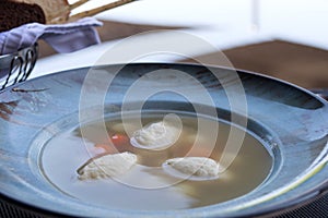 Chicken broth with quenelle. A dish in the form of balls made of minced meat, cream and egg.