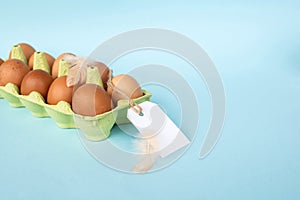 Chicken brown eggs in a recycled cardboard tray with a price tag label. Set of eggs with tag
