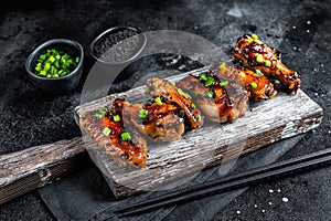 Chicken buffalo wings in sweet and sour sauce with black sesame. Black background. Top view