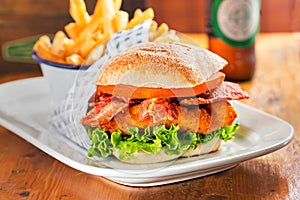 Chicken burger with bacon and lettuce. Fries and beer in restaurant