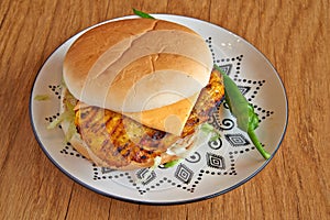 Chicken burger on decorated plate on wooden table