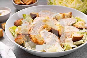 Chicken Caesar Salad in a Bowl with Parmesan Cheese, Dressing and Croutons