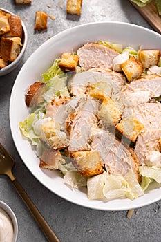 Chicken Caesar Salad in a Bowl with Parmesan Cheese, Dressing and Croutons