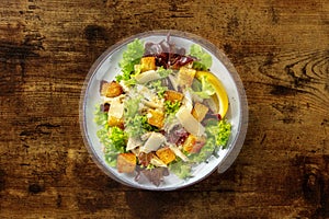 Chicken Caesar salad, overhead shot on a dark rustic wooden background
