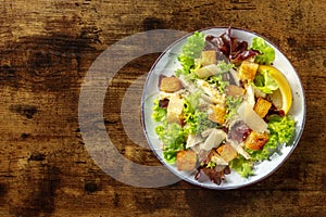 Chicken Caesar salad, overhead shot on a dark rustic wooden background