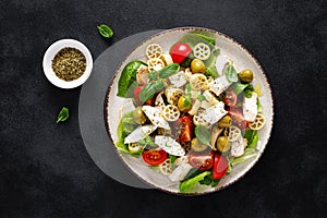 Chicken Caprese pasta salad with mozzarella cheese, olives, tomato and fresh basil. Top view, flat lay