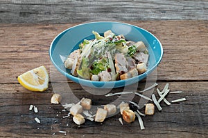 Chicken Cesar salad with croutons, grated cheese and lemon