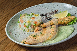 Chicken chops in batter with sauce in a plate with rice and vegetables