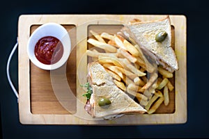 Chicken club sandwich on a white plate with spicy french fries.