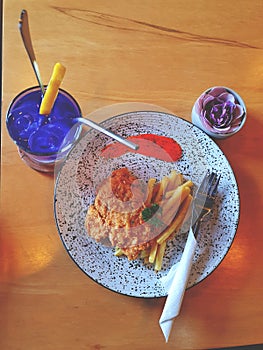 Chicken Cordon bleu and french fries served with drinks on the dining table