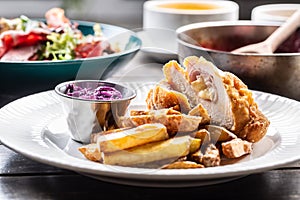 Chicken cordon bleu with ham and cheese inside served with fried potato wedges and red cabbage salad