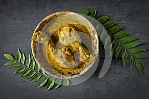 Chicken curry or masala , spicy reddish chicken leg piece dish garnished with coriander leaf and arranged in a white ceramic bowl