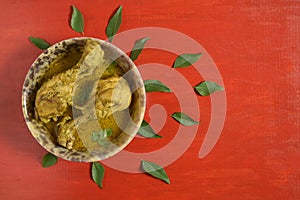 Chicken curry or masala , spicy reddish chicken leg piece dish garnished with coriander leaf and arranged in a white ceramic bowl