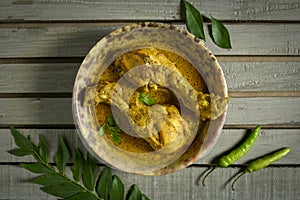 Chicken curry or masala , spicy reddish chicken leg piece dish garnished with coriander leaf and arranged in a white ceramic bowl