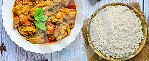 Chicken curry or masala , spicy reddish chicken leg piece dish garnished with coriander leaf and arranged in a white ceramic bowl