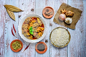 Chicken curry or masala , spicy reddish chicken leg piece dish garnished with coriander leaf and arranged in a white ceramic bowl