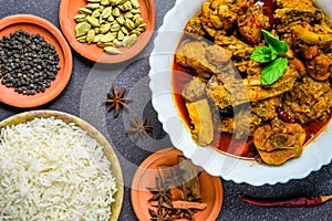 Chicken curry or masala , spicy reddish chicken leg piece dish garnished with coriander leaf and arranged in a white ceramic bowl