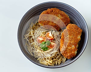 Chicken cutlets with pasta and cherry tomatoes and parsley in a gray plate on a white background. View from above