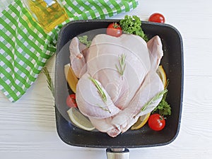 Chicken damp, organic whole poultrydinner in a pan kitchen food preparation on a white wooden background, tomatoes, lemon