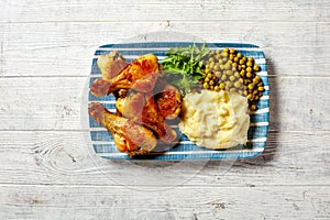 Chicken drumsticks with mashed potato and peas