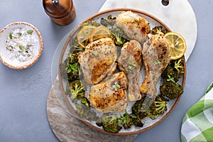 Chicken drumsticks and thighs with broccoli roasted on a serving plate for dinner or lunch