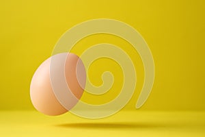 Chicken Egg Falling On Ground Against Yellow Background