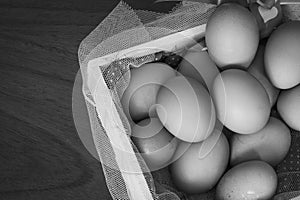 Chicken eggs basket on wooden background white and black