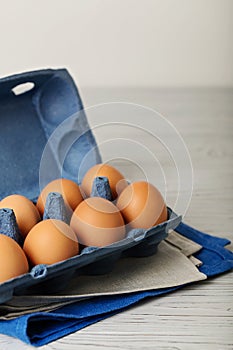 Chicken eggs in a blue package on a gray wooden background.