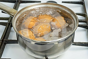 Chicken eggs boil in water. Pan with the product on a gas stove.