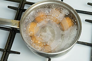 Chicken eggs boil in water. Pan with the product on a gas stove.