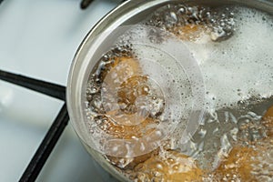 Chicken eggs boil in water. Pan with the product on a gas stove.